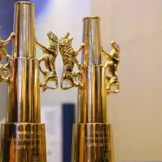 Dwa lśniące, złote puchary z wyrzeźbionymi lwami, symbolizujące prestiżowe Złote Lwy festiwalu filmowego.