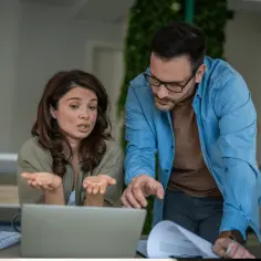Para dyskutuje o 800 plus dla uczących się po 18 roku życia, analizując dokumenty przy laptopie.