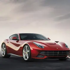 Czerwone Ferrari F12 Berlinetta błyszczy na tle pochmurnego nieba.