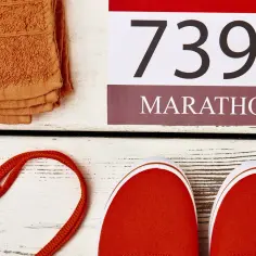 Czerwone buty, pomarańczowy ręcznik i numer startowy 7395. Czy to przygotowania do maratonu?
