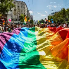 Tęczowa flaga niesiona przez tłum podczas marszu, symbolizująca dumę i wsparcie dla społeczności LGB.