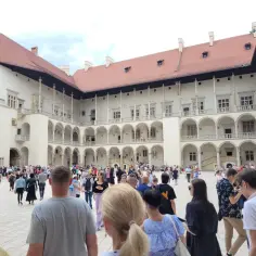 Tłum turystów na dziedzińcu Wawelu. Sprawdzają wawel bilety cennik przed wejściem.