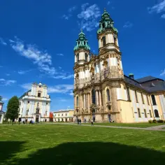 Barokowy kompleks klasztorny z imponującą bazyliką, jeden z ważnych sanktuariów maryjnych w Polsce, na tle błękitnego nieba.