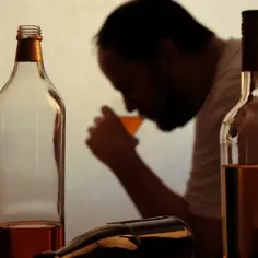 Smutny mężczyzna pije alkohol. Wokół butelki, zastanawia się, renta alkoholowa ile wynosi.