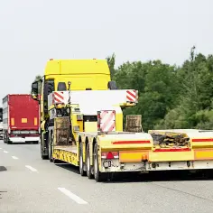 Korek na autostradzie, żółta ciężarówka z niskopodwoziową naczepą i czerwony tir. Zakaz dla ciężarówek w tym miejscu?