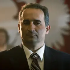 Michał Koterski w garniturze, na tle godła Polski. Widać go w jednym z filmów, gdzie gra poważną rolę.