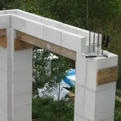 Budowa domu z bloczków z betonu komórkowego. Widoczne kształtki wieńcowe Solbet, zbrojenie i drewniane wsporniki.