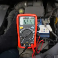 Multimetr pokazuje 12.72V. Sprawdzamy, jak sprawdzić czy alternator ładuje, mierząc napięcie na akumulatorze.