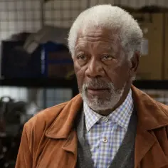 Morgan Freeman w brązowej kurtce i kratowanej koszuli, jak z jego filmów.
