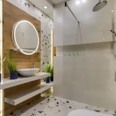 Nowoczesne oświetlenie LED łazienki podkreśla aranżacje z terazzo i drewnem. Okrągłe lustro z podświetleniem LED dodaje elegancji.