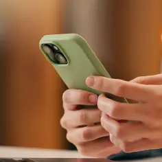 Dłonie trzymające zielony telefon komórkowy.