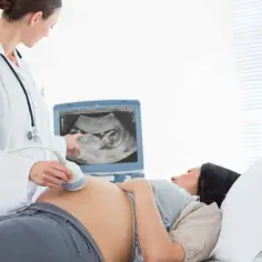 Lekarz wykonuje USG ciężarnej. Regularne wizyty u ginekologa w ciąży są kluczowe dla zdrowia mamy i dziecka.