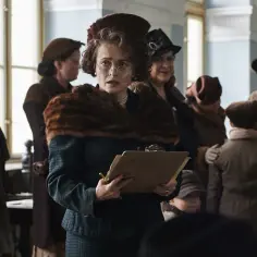 Helena Bonham Carter w filmach, w roli kobiety z tablicą, otoczona ludźmi w strojach z epoki.