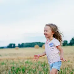 Szczęśliwa dziewczynka biega po polu. Czy dziecko musi iść do przedszkola, gdy świat jest tak piękny?