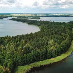 Widok z lotu ptaka na jezioro otoczone lasem i pola w oddali.
