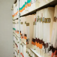 Archiwum akt pacjentów, gdzie każdy folder to historia nazwiska i jego losów.