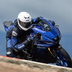 Motocyklista w kombinezonie Yamahy pochyla się na torze na sportowym motocyklu Yamaha YZF-R125. Dane techniczne tego modelu są imponujące.