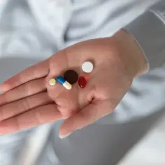 Dłoń trzyma garść tabletek i kapsułek, które mogą być lekami na receptę na insulinooporność.