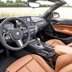 Wnętrze BMW f23 z brązową skórzaną tapicerką i sportową kierownicą.