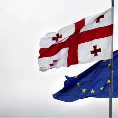 Flagi Gruzji i Unii Europejskiej powiewają na wietrze, symbolizując aspiracje Gruzji i jej obecną sytuację polityczną.