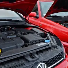 Dwa czerwone Volkswageny z otwartymi maskami. Widać silnik TDI, czyli silnik diesla, w nowszym modelu i starszy silnik w Golfie III.