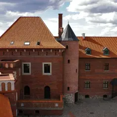 Zamek w Tykocinie zaprasza na zwiedzanie. Czerwona cegła, wieże i pomarańczowe dachy tworzą malowniczy widok.