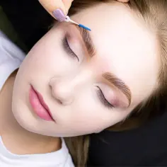 Krok po kroku laminacja brwi w domu. Delikatny pędzelek układa włoski, nadając im perfekcyjny kształt.