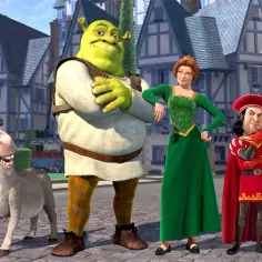 Shrek, Fiona, Osioł i Lord Farquaad stoją razem na brukowanej uliczce. Te kultowe shrek postacie z bajki wyglądają na gotowe do przygody.