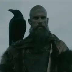 Floki, wiking z długą brodą, z krukiem na ramieniu, patrzy w dal.
