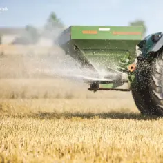 Traktor rozsiewa wapno węglanowe na polu.