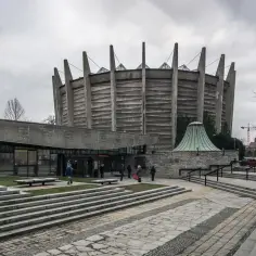 Monumentalna budowla w stylu brutalizm architektura, z betonowymi żebrami i szklanym wejściem.