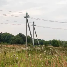 Słupy energetyczne i wieża telekomunikacyjna na tle nieba. Zastanawiasz się, ile pieniędzy za słup na działce?