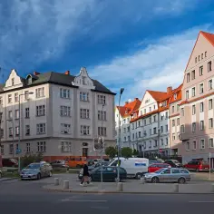 Kamienice w Wałbrzychu, gdzie ceny mieszkań mogą być atrakcyjne. Ulica z samochodami i błękitnym niebem.