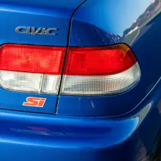Niebieski tył Hondy Civic Si z chromowanym napisem CIVIC i czerwonym znaczkiem Si.