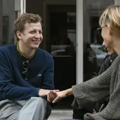 Maciej Musiałowski z partnerką, uśmiechnięci, siedzą blisko siebie, trzymając się za ręce.