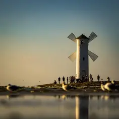 Biała latarnia morska w kształcie wiatraka, jedna z głównych promenada Świnoujście atrakcje, na tle zachodzącego słońca.