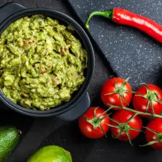Miseczka guacamole z awokado, pomidorkami, limonką i papryczką chili.