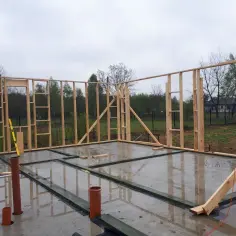 Drewniana konstrukcja ścian w budowie, widoczne mocowanie podwaliny do fundamentu.