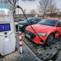 Dwa samochody elektryczne, czerwony i ciemnozielony, ładują się na stacji Ionity. Ekran pokazuje dane o ładowaniu, co pozwala ocenić koszt ładowania samochodu elektrycznego.
