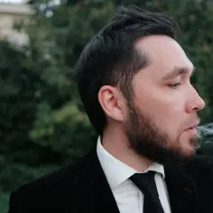 Mężczyzna w garniturze wydycha dym. Szukasz najskuteczniejszych metod na pozbycie się zapachu papierosów z ubrań bez prania?