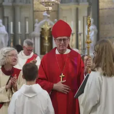 Biskup w czerwonej szacie i mitrze, z pastorałem, podczas uroczystości. Różnice między kościołem starokatolickim a rzymskokatolickim są widoczne w liturgii.