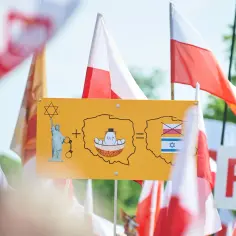 Symboliczna tablica z napisem "ustawa 447" i grafikami: Statua Wolności, Polska, Izrael.
