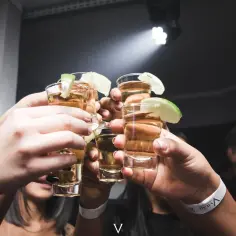 Ludzie wznoszą toast kieliszkami z tequilą lub mezcalem, zastanawiając się nad różnicą między nimi w klasycznej margaricie.