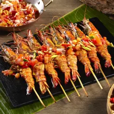 Szaszłyki z krewetek na grilla, podane z salsą pomidorową i papryczkami chili.