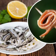 Anchois na talerzu i na wykałaczce, obok cytryny i ziół.