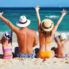 Rodzina na plaży, machająca rękami. Idealne miejsce na śmieszne życzenia na wakacje!