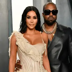 Kim Kardashian i jej mąż, Kanye West, pozują do zdjęcia w eleganckich strojach.