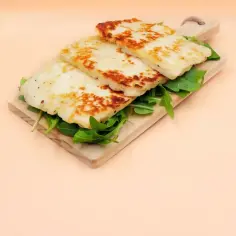 Grillowany ser halloumi na desce z rukolą. Idealny pomysł na szybkie i pyszne przepisy z halloumi.