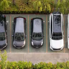 Widok z góry na rząd samochodów na parkingu. Odległość miejsc postojowych od budynku jest niewielka, co ułatwia dostęp.