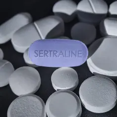 Fioletowa tabletka z napisem SERTRALINE wśród białych tabletek. Zotral 50 pomaga w walce z depresją.